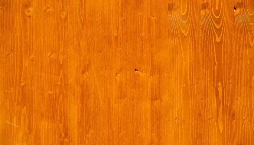 Orange gebeiztes Birken-Weichholz mit sichtbarer Maserung und Astlöchern.