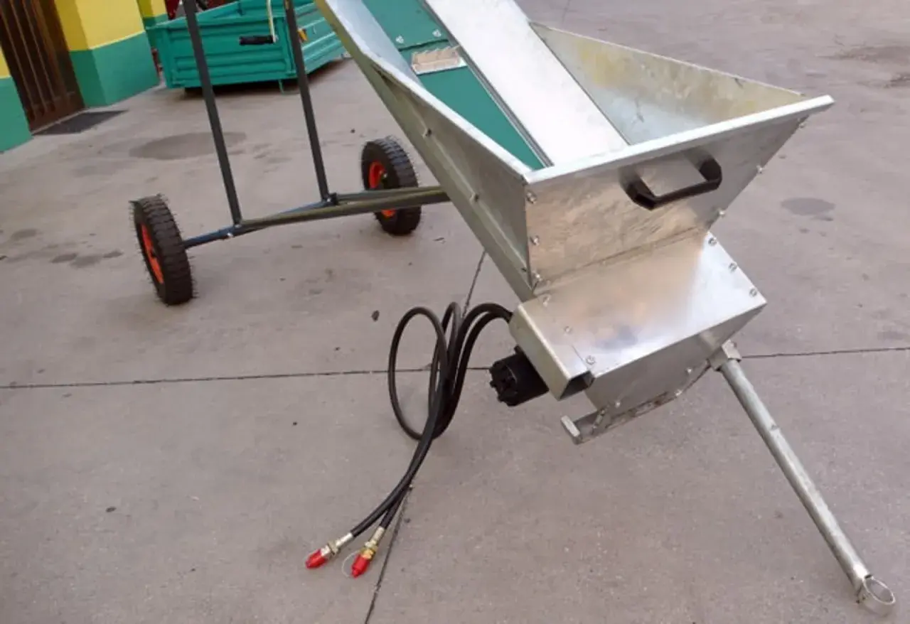 Ein mobiler **förderband hydraulisch** mit Metalltrichter und Rädern, bereit für den Einsatz.