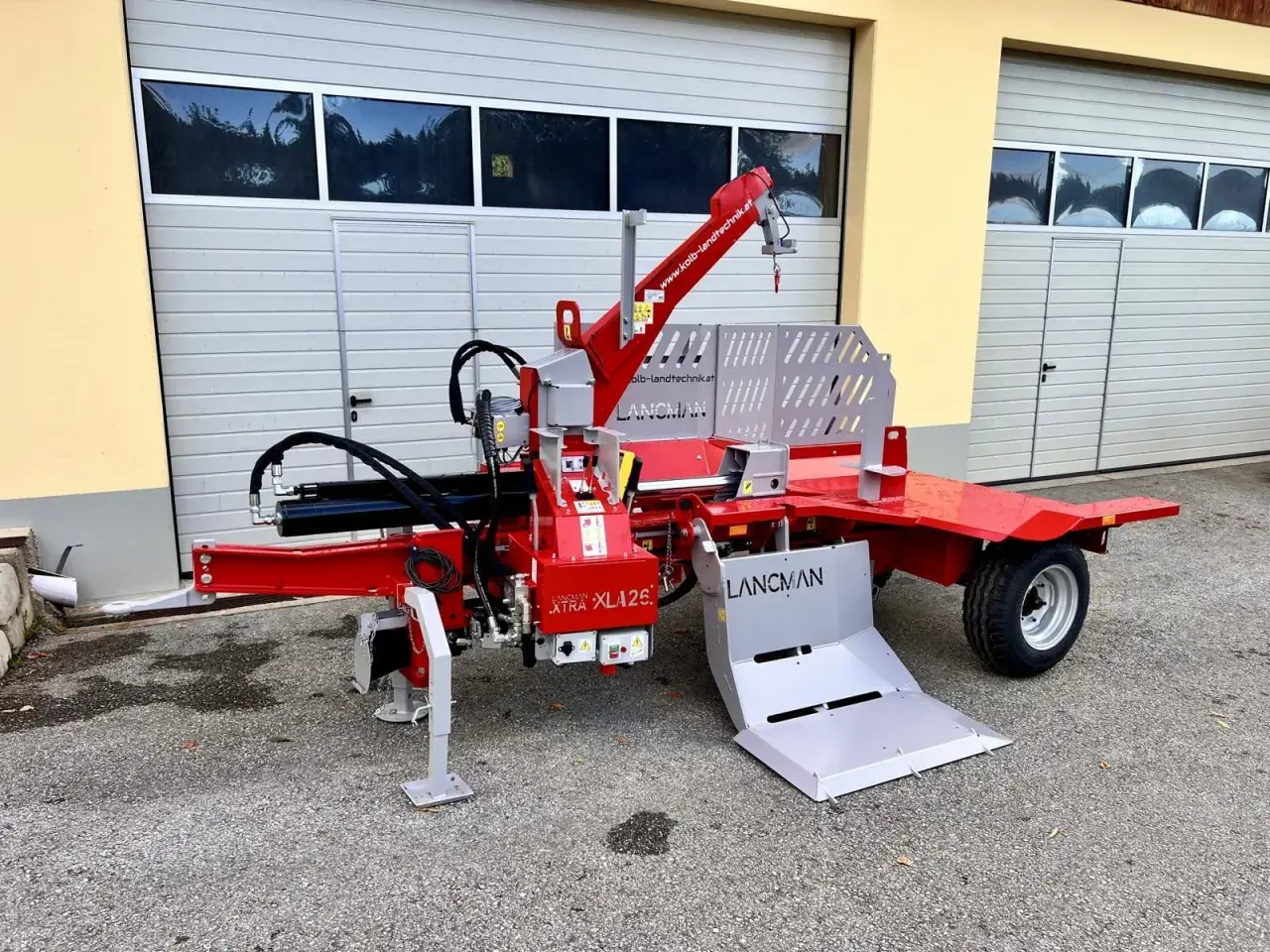 Roter Holzspalter mit Seilwinde, Kran und Auswurf. Ideal für die effiziente Holzverarbeitung.
