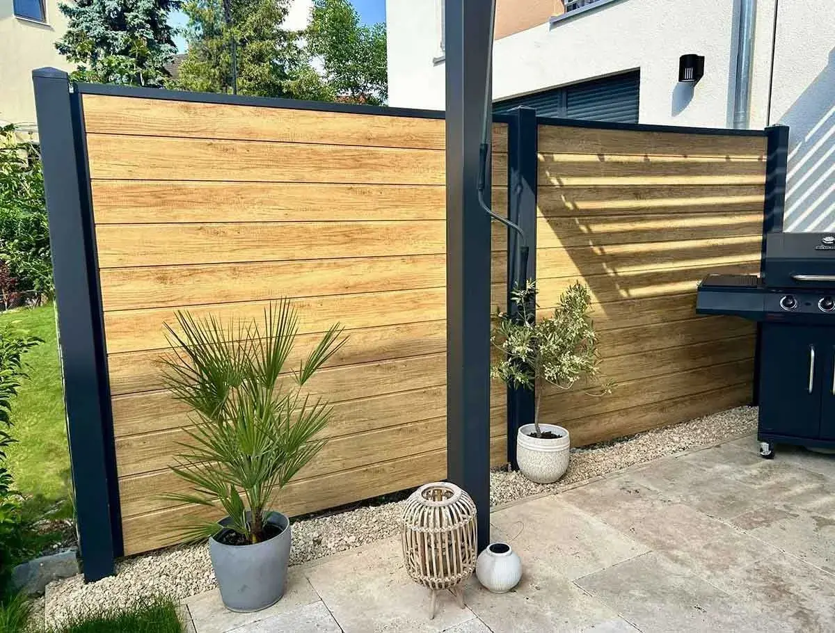 Moderner Sichtschutz aus Holz, ideal zum selber bauen. Ein Grillplatz mit stilvoller Holzwand und Pflanzen.