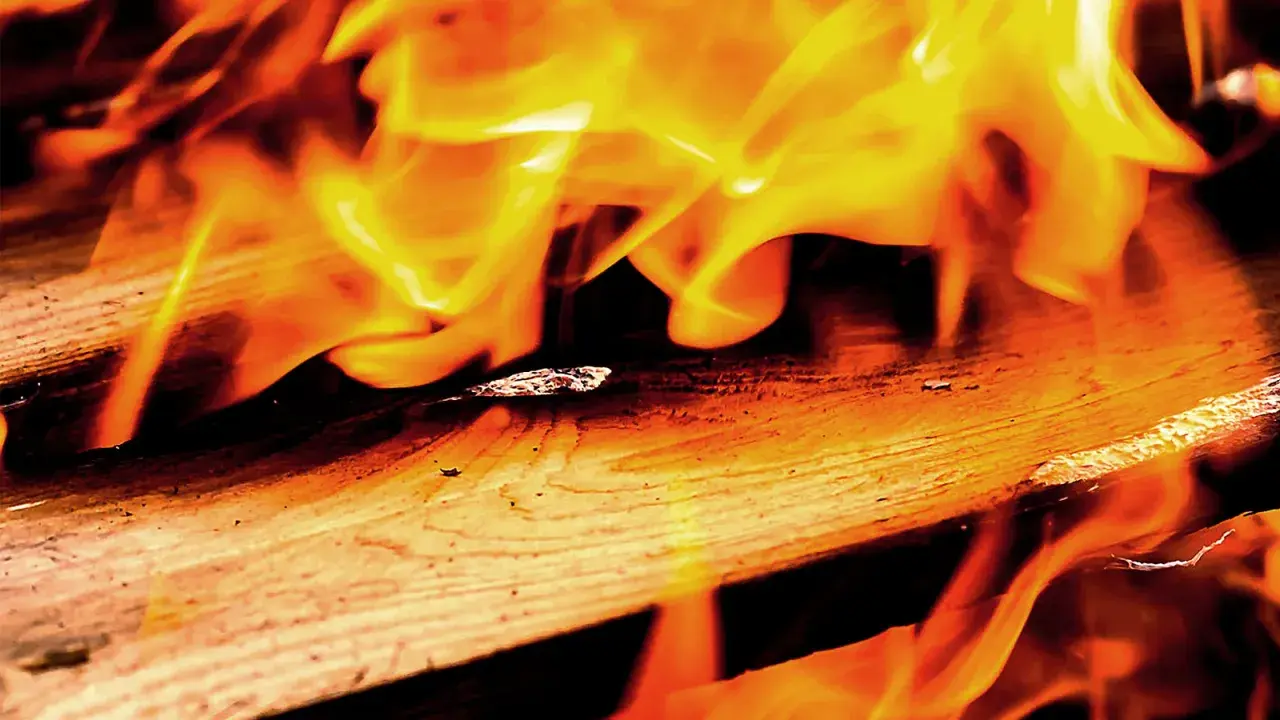 Flammen tanzen über Holz. Lackiertes Holz verbrennen giftig, hinterlässt Asche und Rauch.