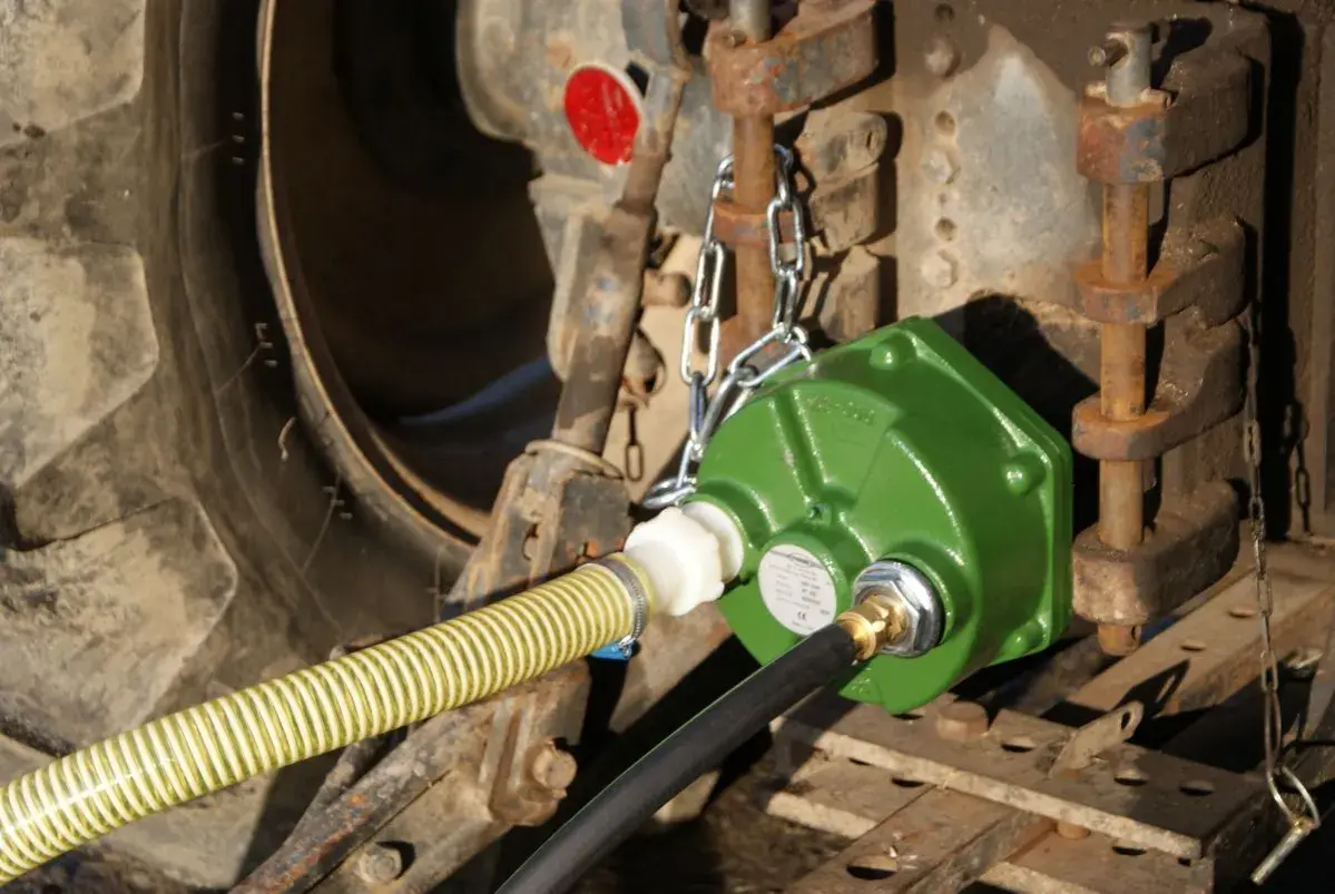Grüne Zapfwellenpumpe mit Schläuchen an einem Traktor.