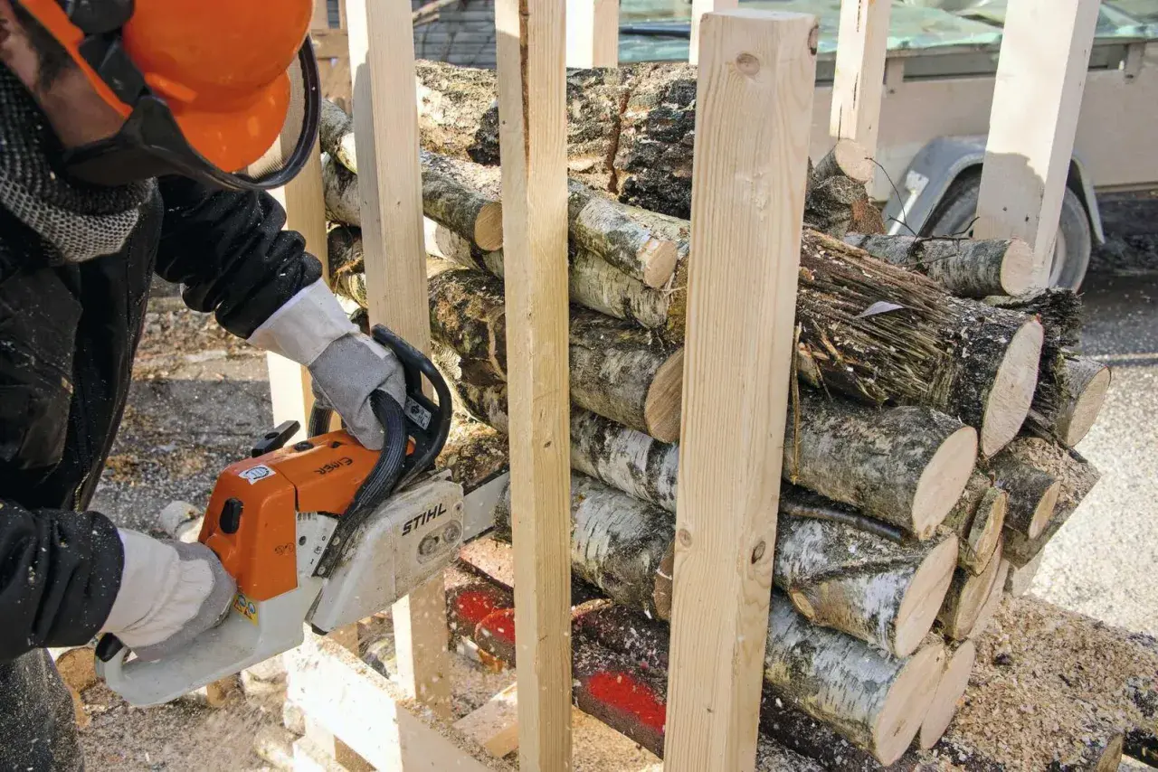 Mann mit Kettensäge bereitet brennholz sägen vor. Holzscheite sind gestapelt und werden für den Winter vorbereitet.
