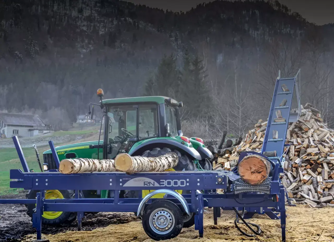 Ein Taifun Holzspalter mit Traktor im Hintergrund, bereit, einen großen Holzstapel zu verarbeiten.