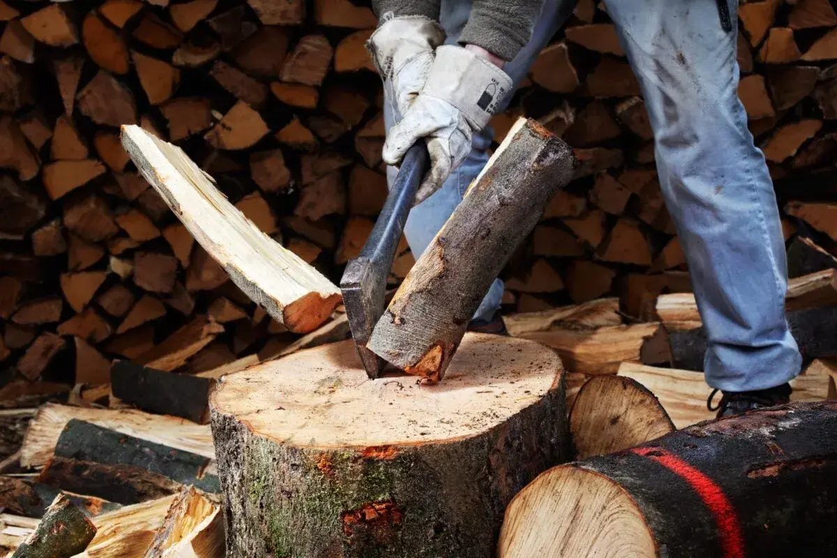 Mann spaltet Holz mit Axt. Mit der richtigen Technik kann man den Holzspalter schneller machen und effizienter arbeiten.