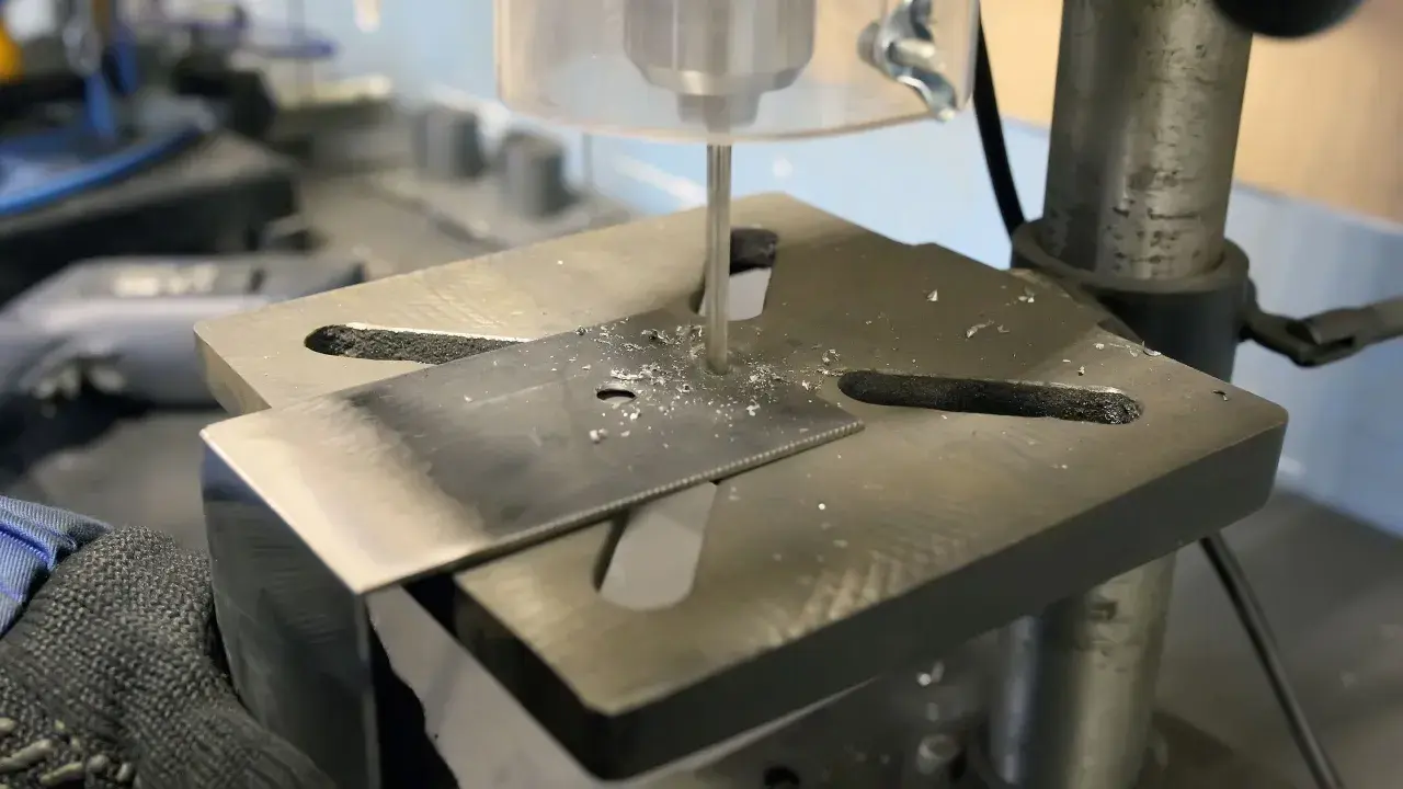Detailaufnahme des Aufbaus einer Standbohrmaschine, die ein Metallstück bohrt.