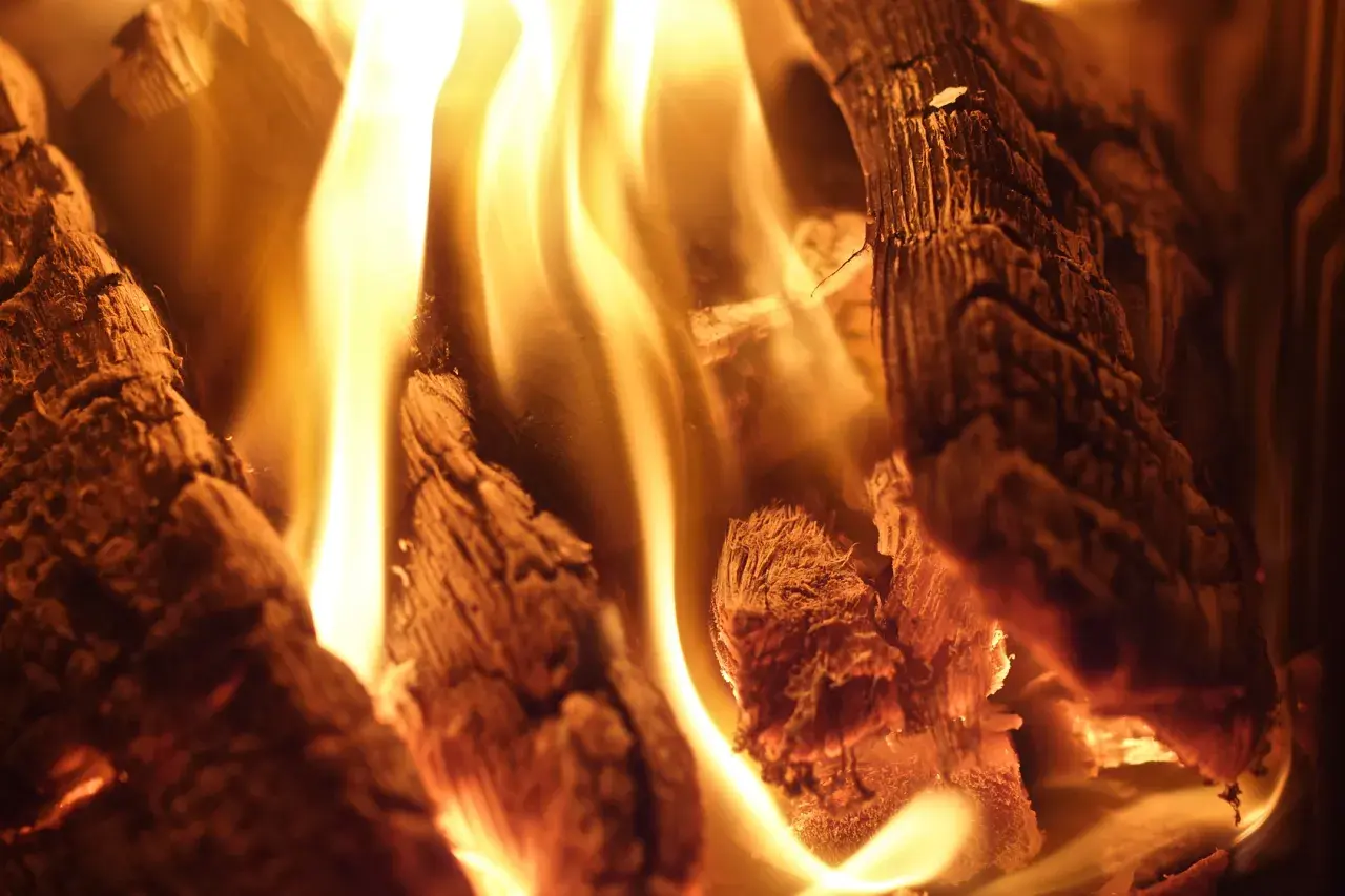 Glühende Flammen tanzen um das Teakholz, das langsam verbrennt und eine warme, gemütliche Atmosphäre schafft.