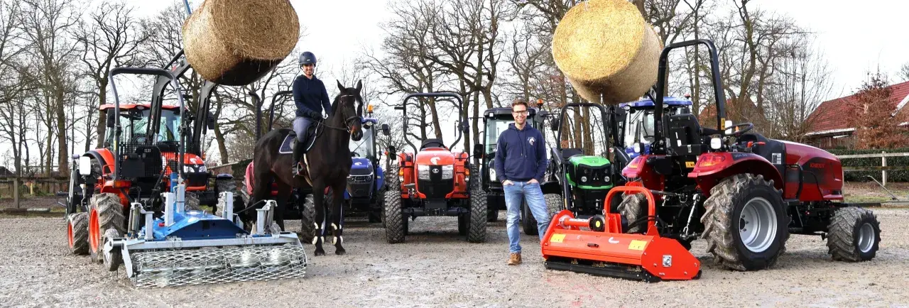 Ein Mann und eine Frau mit einem Pferd stehen vor mehreren Traktoren. Ein kleiner forsttraktor ist im Vordergrund zu sehen.