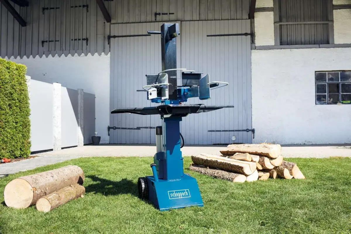Scheppach Holzspalter Öl nachfüllen: Ein blauer Holzspalter steht auf einem Rasen, daneben liegen Holzscheite.