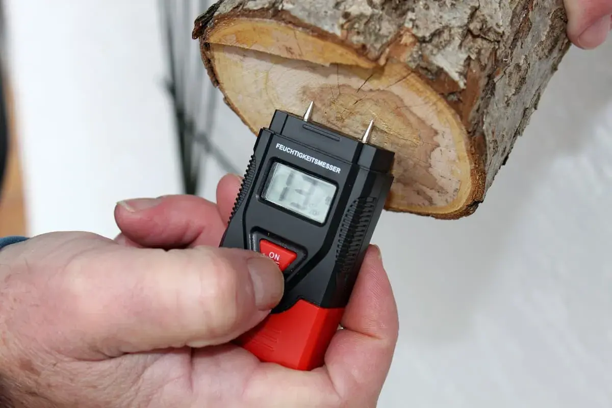 Ein Feuchtigkeitsmesser misst den Feuchtigkeitsgehalt von Brennholz. Die Anzeige zeigt 13%.