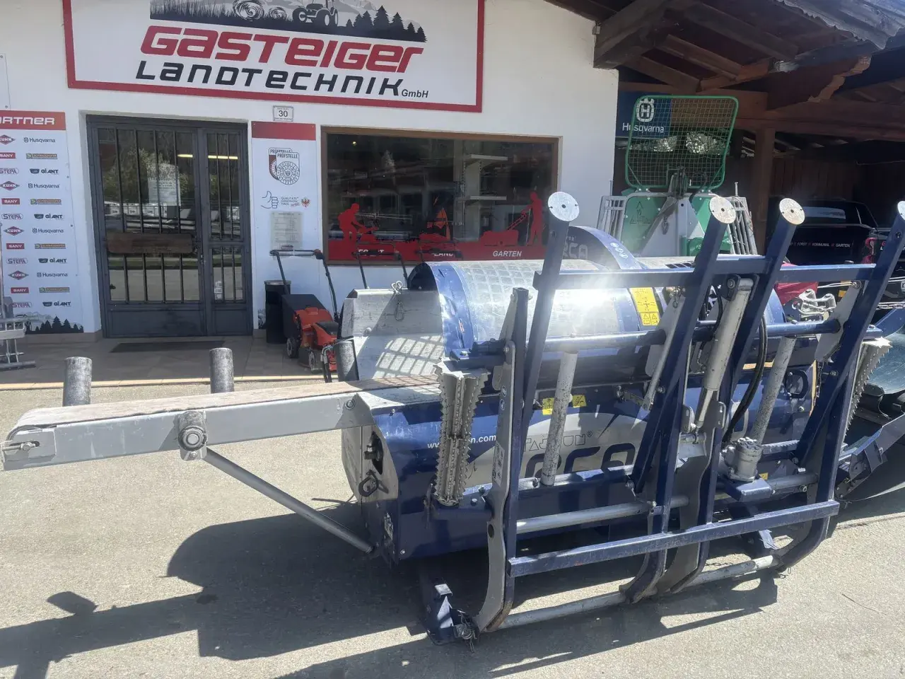 Blauer Holzspalter Tajfun RCA 400 gebraucht vor einem Landtechnikgeschäft.