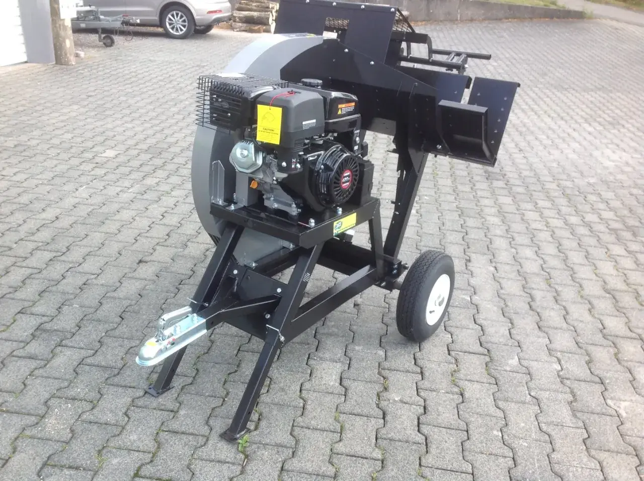 Robuste wippsäge mit benzinmotor, bereit für den Einsatz im Garten oder Wald. Mit Anhängerkupplung und Rädern für einfachen Transport.
