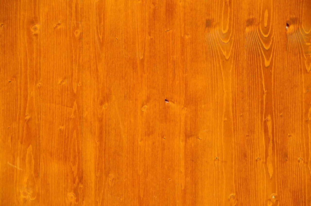 Orange gebeiztes Birken-Weichholz mit sichtbarer Maserung und Astlöchern.