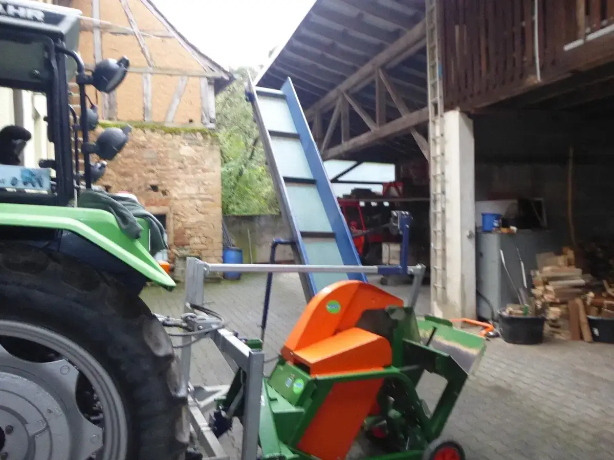 Gebrauchte Kreissäge mit Förderband, bereit für den Holzeinschlag. Ein Traktor steht daneben.