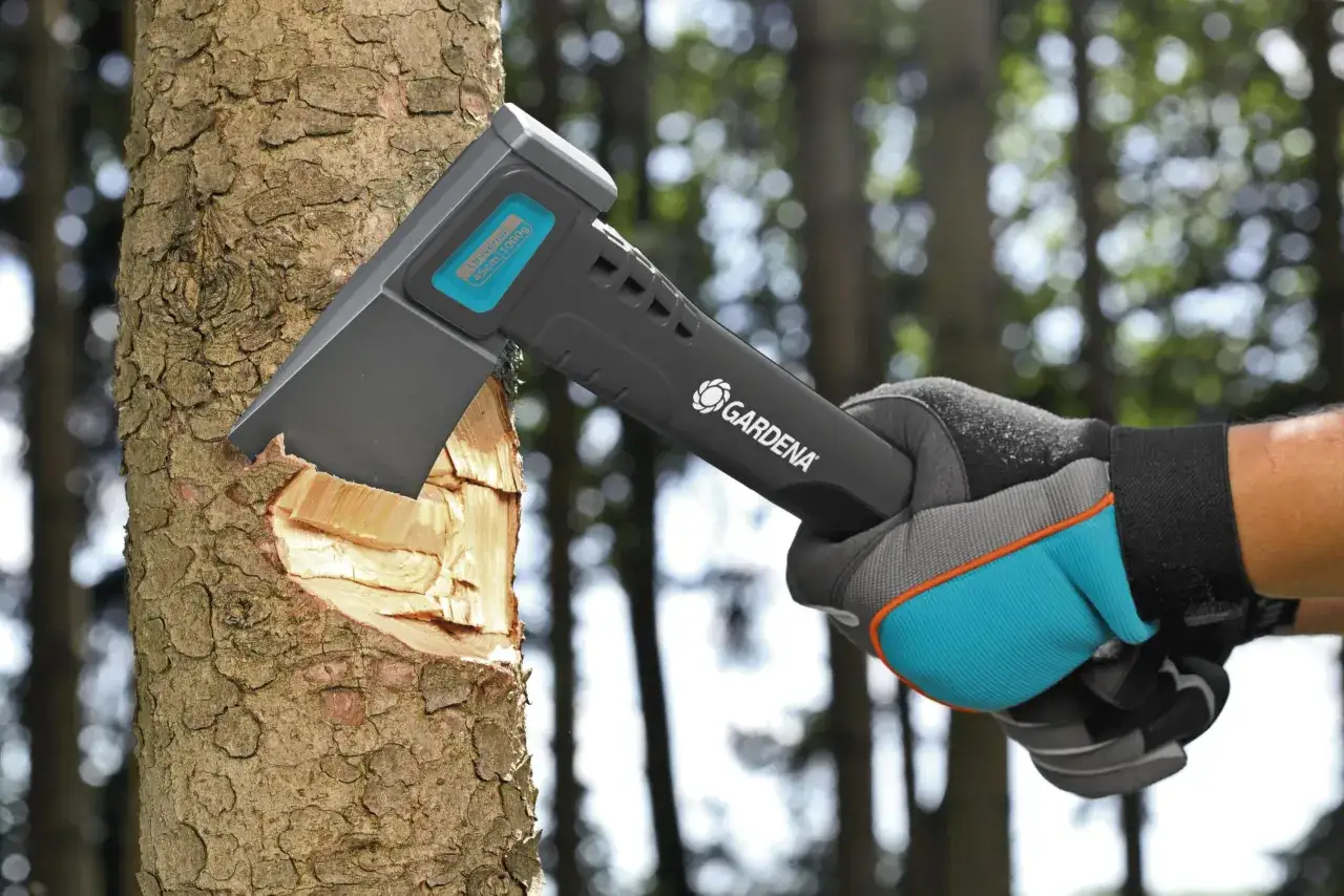 Gartenhandschuh hält ein Gardena Beil, das gerade Holz spaltet.