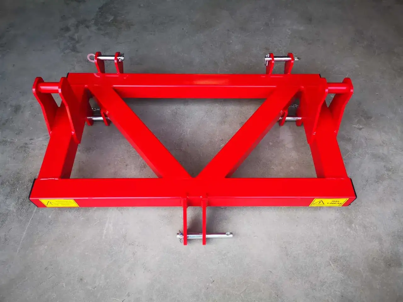 Roter Dreipunktadapter mit stabilen Stahlstreben und Sicherungspins, bereit für den Einsatz auf dem Feld.