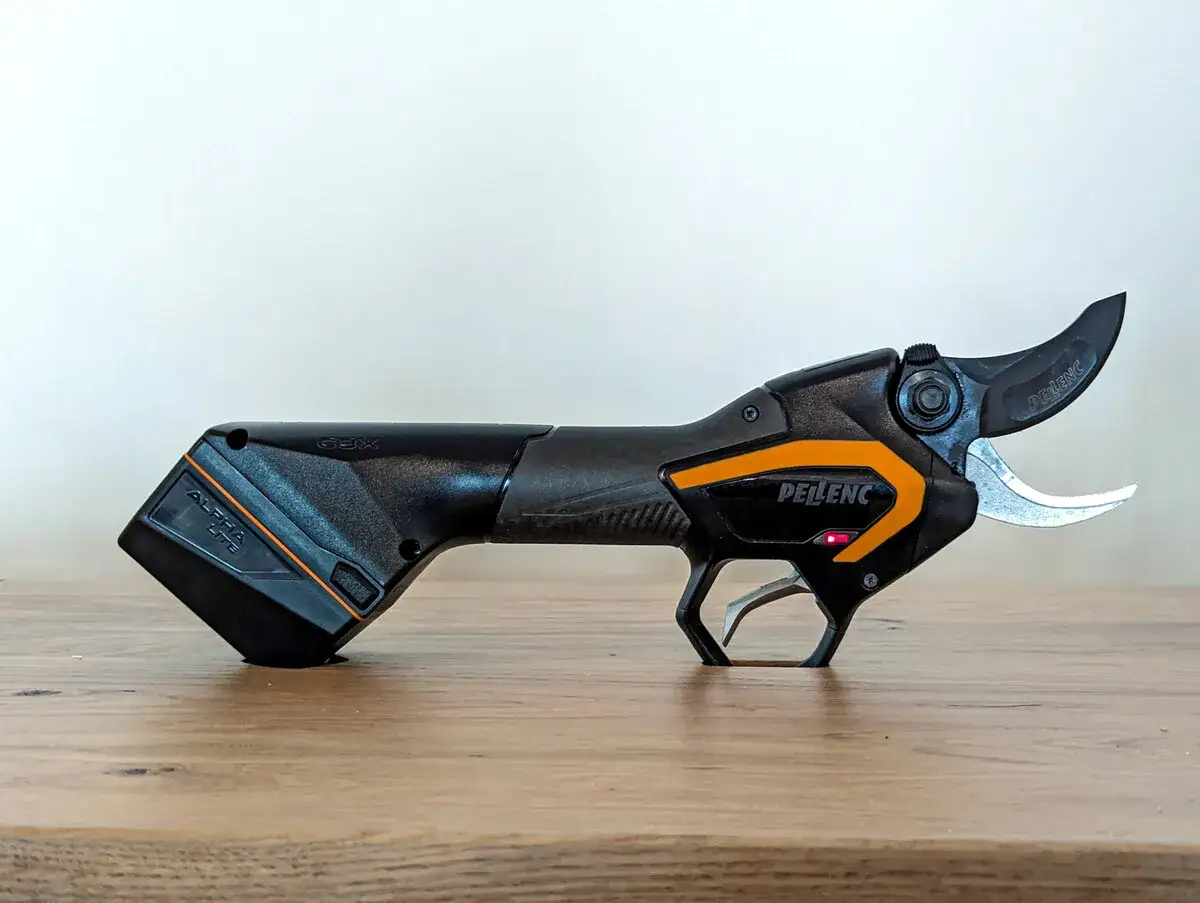 Professionelle akku rebschere von Pellenc, Modell Alpha LITE, liegt auf einem Holztisch.