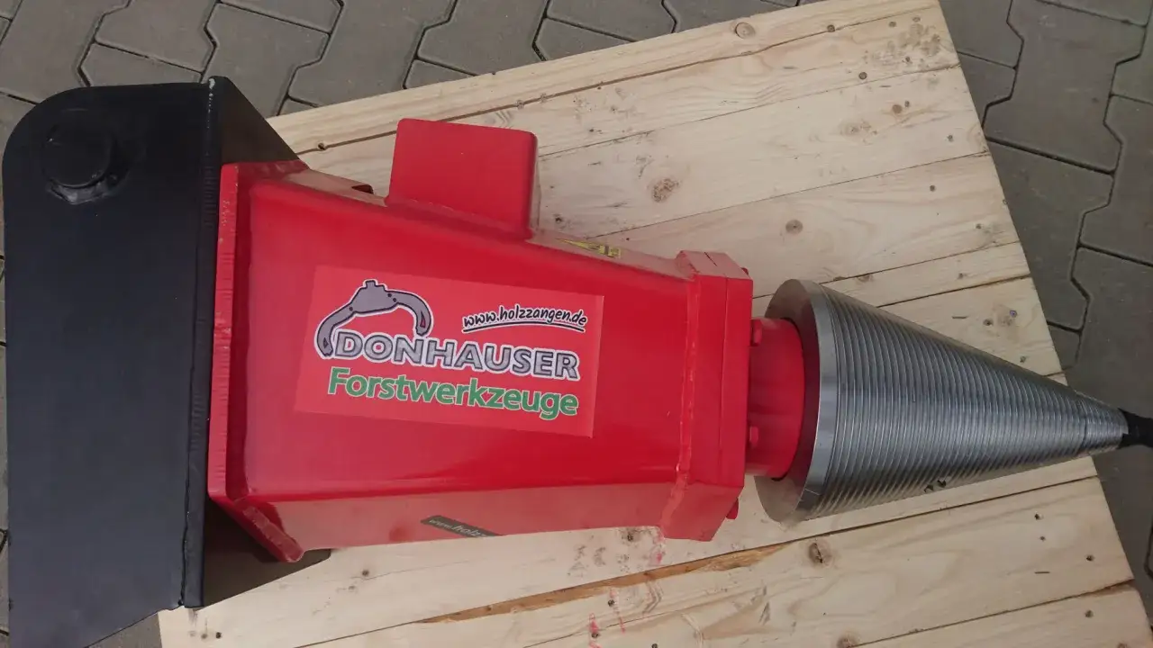 Roter Kegelspalter mit schwarzem Anbau, bereit für den Einsatz. Der Kegelspalter ist ein leistungsstarkes Werkzeug, das zum Spalten von Holz verwendet wird.