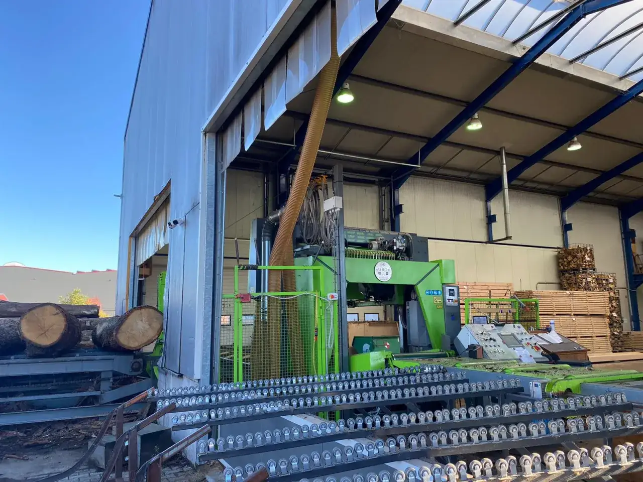 Große, grüne blockbandsäge in einer Holzverarbeitungsanlage, bereit, Baumstämme zu zuschneiden.