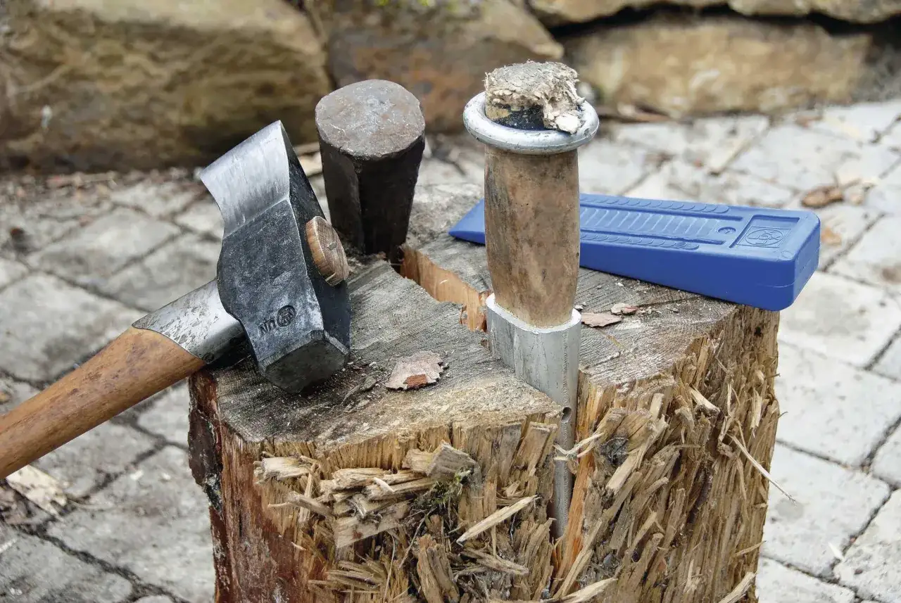 Werkzeug zum Baumstamm spalten mit Keil: Beil, Spaltkeil und Hammer liegen bereit, um Holz zu zerkleinern.