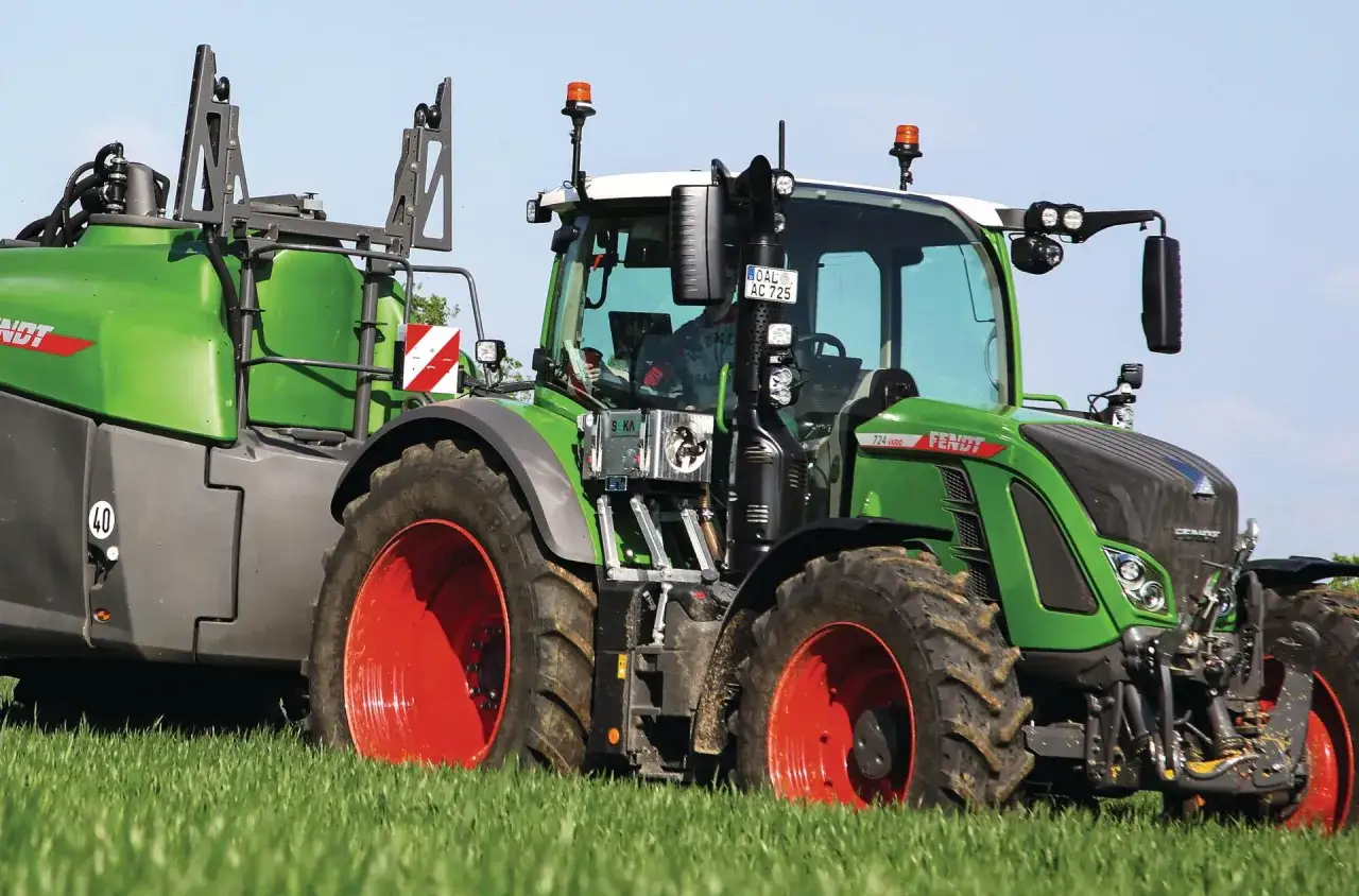 Grüner Fendt-Traktor mit Anhänger im Feld. Die universellen Kabinen für Traktoren bieten Komfort und Sicherheit.