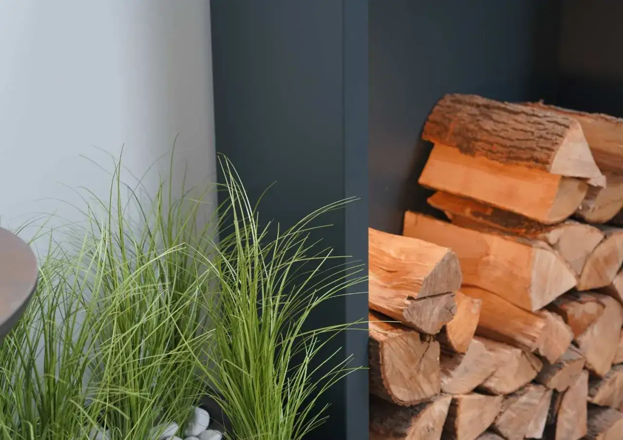 Grünes Gras neben einem Stapel Holz. Dieses Holz ist erle, gutes Brennholz für gemütliche Abende.