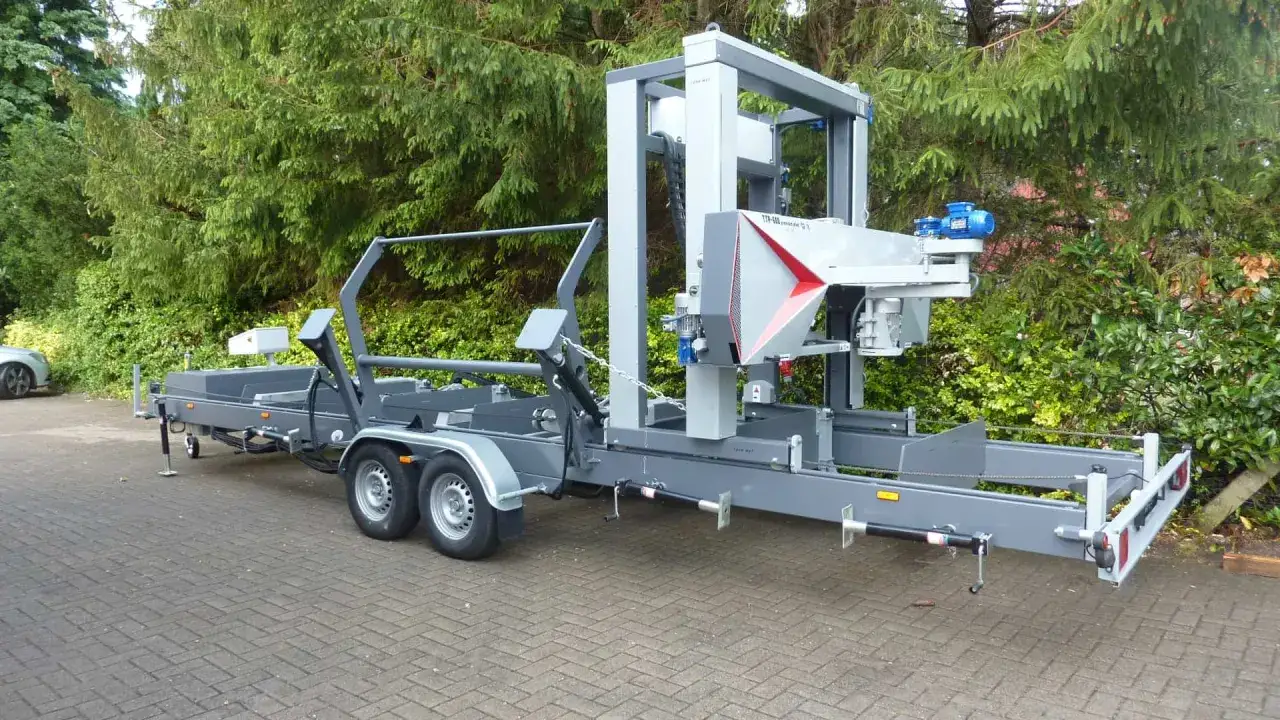Mobile blockbandsäge auf einem Anhänger, bereit für den Einsatz im Wald.