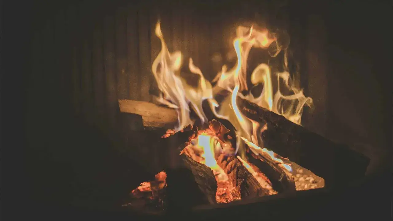 Flammen tanzen um Holzscheite im Kamin. Es sieht aus, als ob das Holz brennt nicht, aber die Wärme ist spürbar.