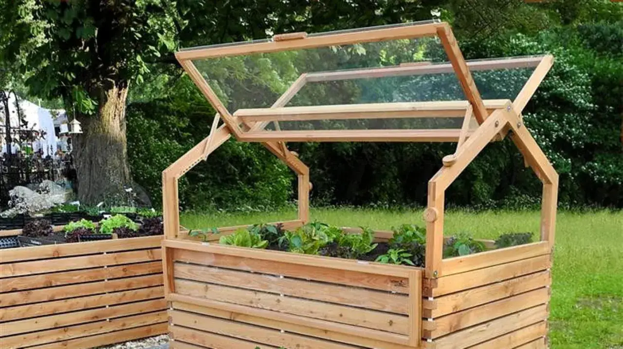Ein hölzernes Hochbeet mit Glasabdeckung, ideal zum kinderleicht selber bauen von Kräutern und Gemüse.