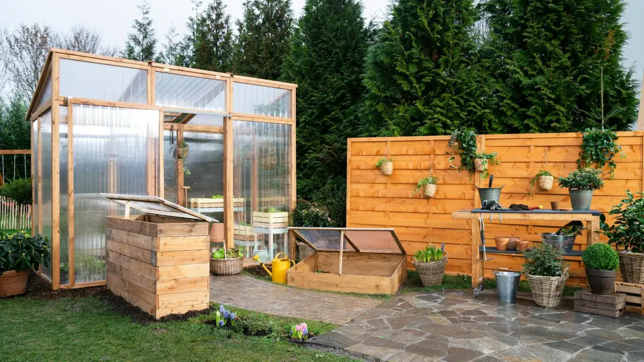 Ein Garten mit einem selbstgebauten Tomatenhaus, Frühbeet und Werkbank. Perfekt für Hobbygärtner, die ihr eigenes Gemüse anbauen wollen.