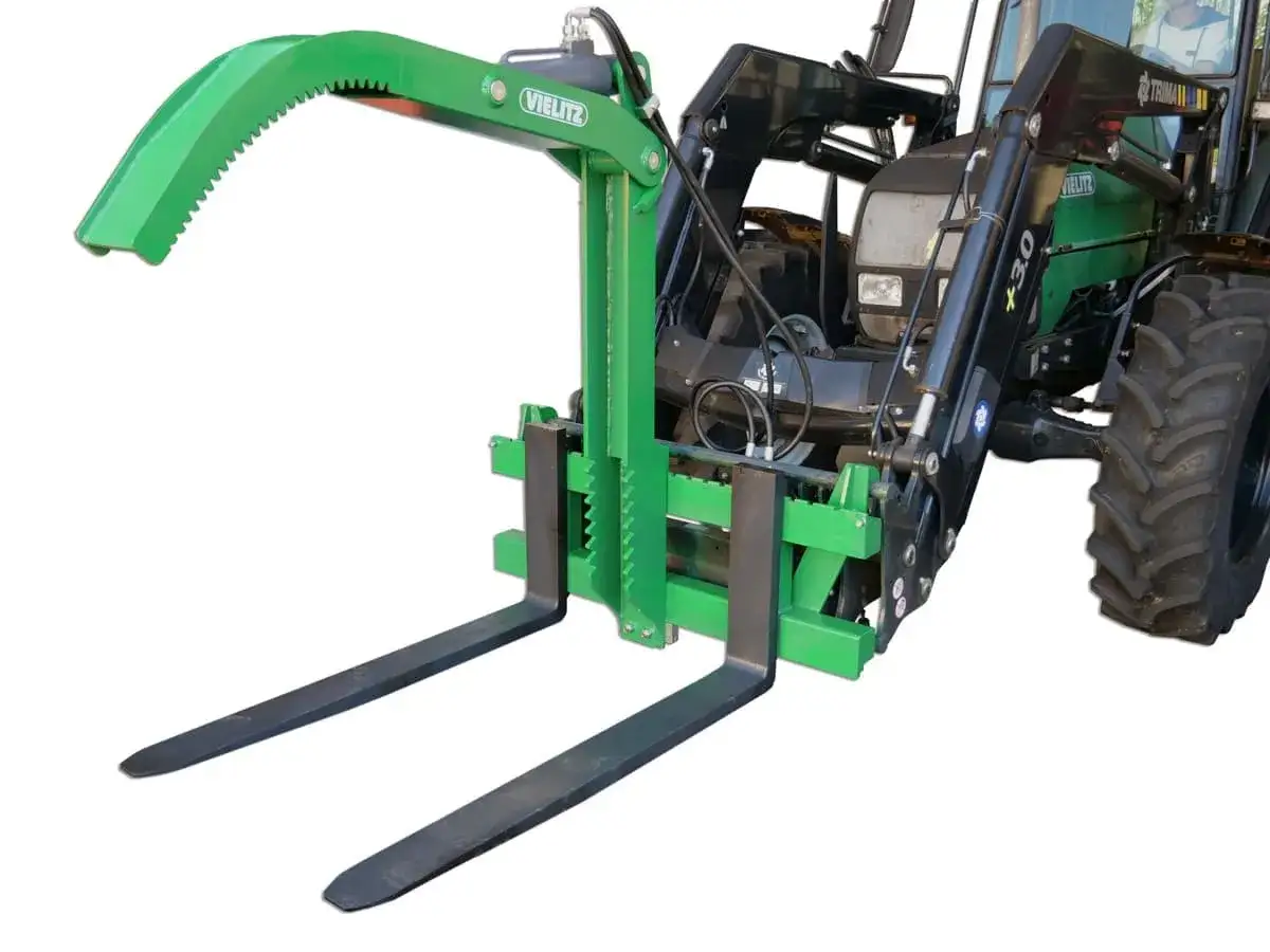 Grüne Verladeschaufel mit Zinken und Gabeln, bereit für den Einsatz auf einem Traktor.