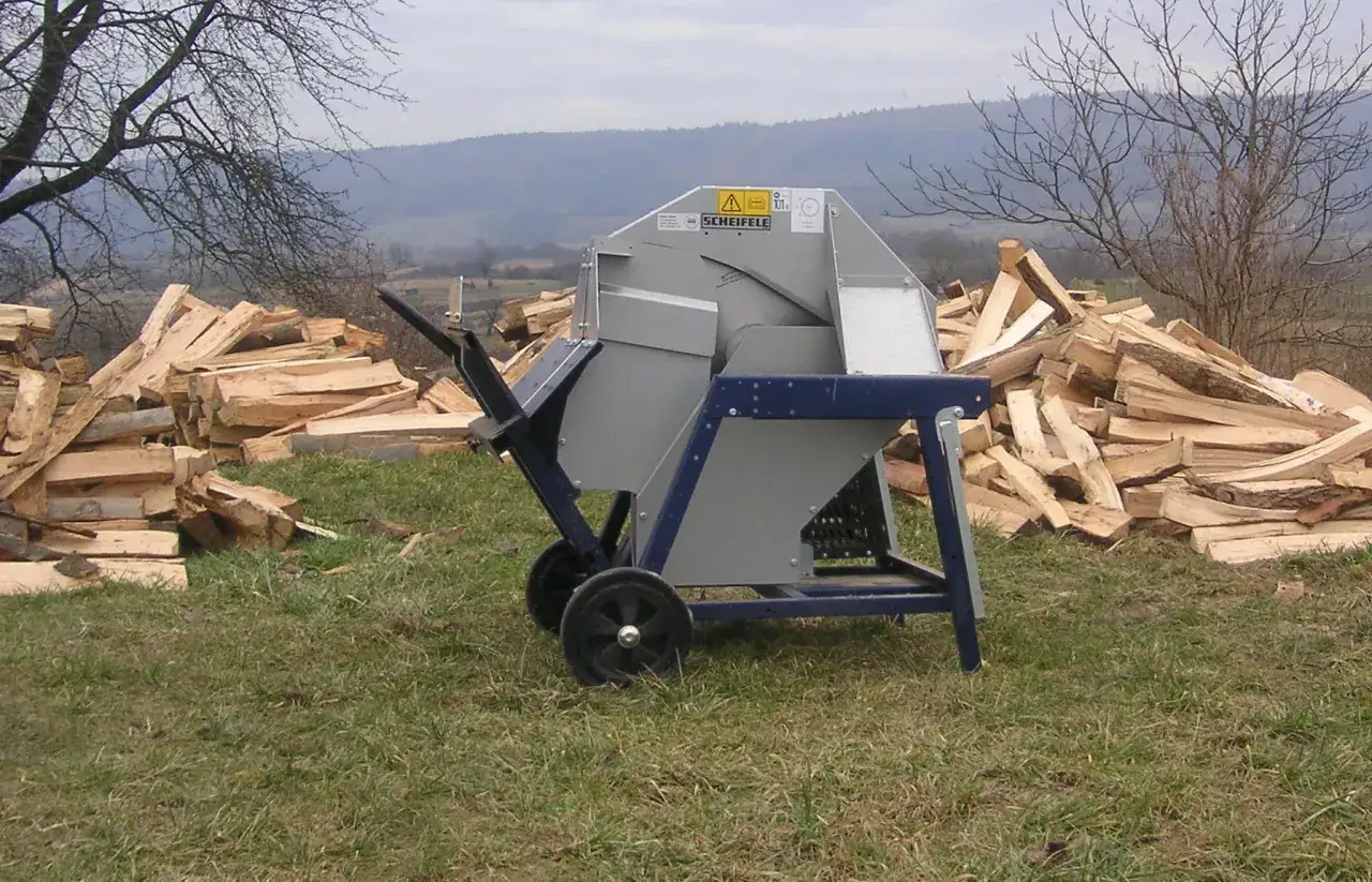 Scheifele Wippsäge steht bereit, um Holzscheite zu schneiden. Berge von Holz liegen daneben.