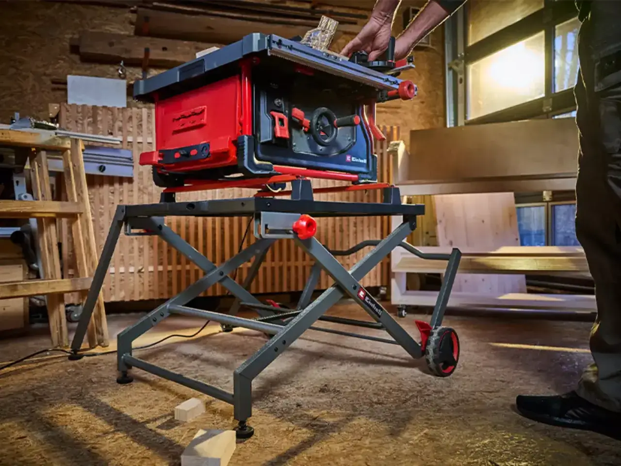 Eine mobile Kreissäge auf einem klappbaren Untergestell mit Rädern, bereit für den Holzschnitt in einer Werkstatt.