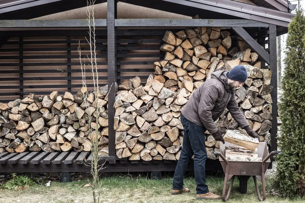 Mann l&auml;dt Holz f&uuml;r den Winter. Die Frage nach der brennholz trocknen dauer und eine passende tabelle sind hier relevant.