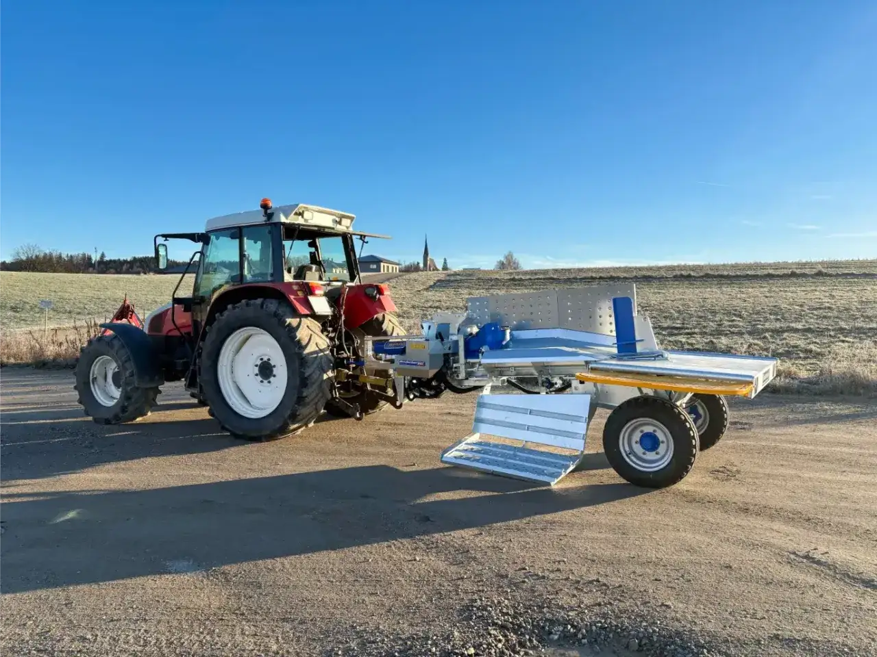 Traktor mit Binderberger WS 700 Zapfwelle, bereit für den Holzeinsatz im Freien.