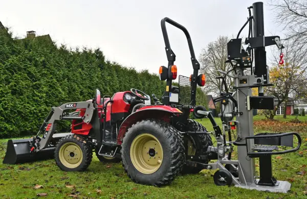 Roter Traktor mit Frontlader und einem liegenden Holzspalter gebraucht 30t im Garten.